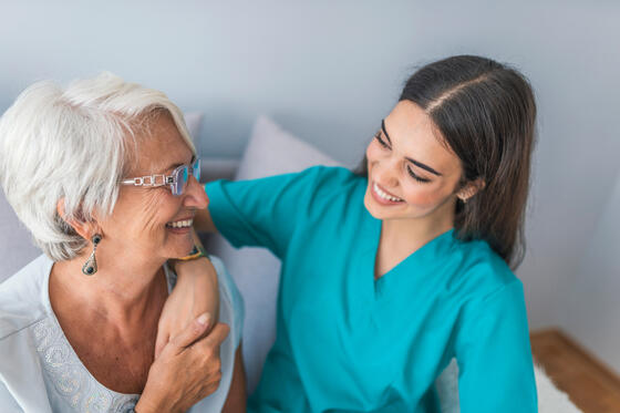 Nurse smiling with female patient, holding her hand